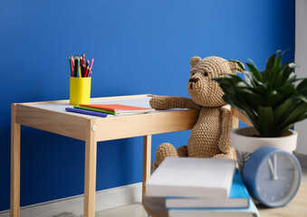 Table with stationery and teddy bear in children's room