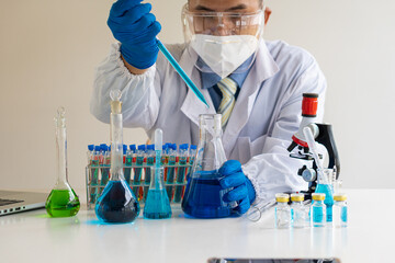 Fototapeta premium A biochemical research scientist working to develop a vaccine against coronavirus in a drug research laboratory holding a vial with glassware. Research and development concepts in science laboratories