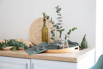 Vases with eucalyptus branches on counter in kitchen