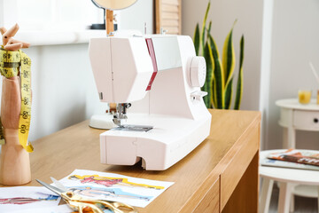 Modern sewing machine on wooden table in atelier