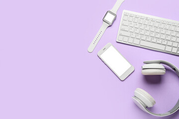 Modern headphones, keyboard, mobile phone and smart watch on color background