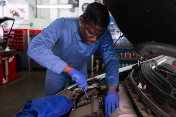 Fototapeta na wymiar Skilled mechanic technician working at service station, repairing car