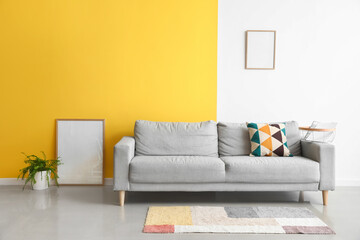 Interior of stylish living room with grey sofa and blank frames