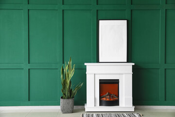 Fireplace with blank frame and houseplant near green wall