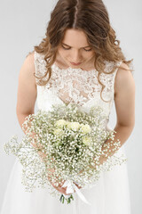 Beautiful bride with bouquet of flowers on light background