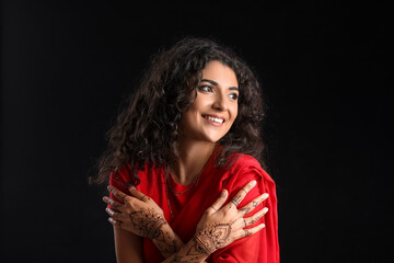Beautiful Indian woman with henna tattoo on dark background