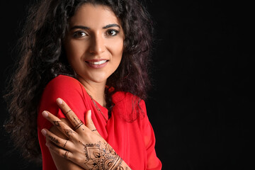 Beautiful Indian woman with henna tattoo on dark background