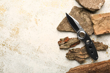 Folding pocket knife with rubberized handle lying on stones and tree barks