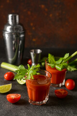 Glasses of bloody mary with celery, lime and tomatoes on table
