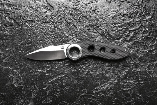 Folding pocket knife with rubberized handle on black textured background