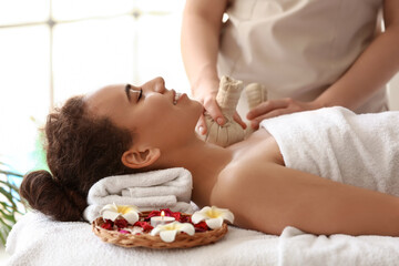 Young African-American woman getting facial massage in spa salon