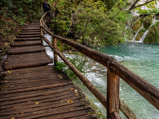 Fototapeta na wymiar Wooden walkway to traverse a cascade running from lake to lake in the Plitvice Lakes District, Croatia.