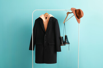 Rack with modern clothes and accessories on color background