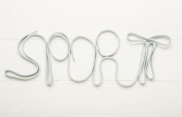 Word SPORT made of shoe laces on color wooden background