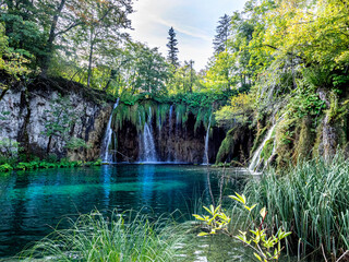 Waterfalls into a lake surrounded by foliage in the Plitvice Lakes district, Croatia. 