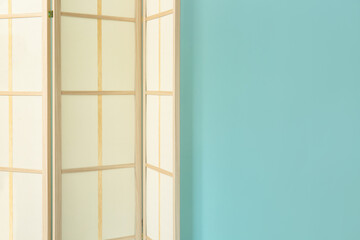 Modern folding screen near blue wall