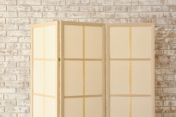 Beige folding screen near light brick wall