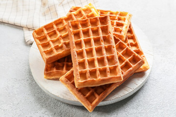 Board with tasty golden Belgian waffles on light background