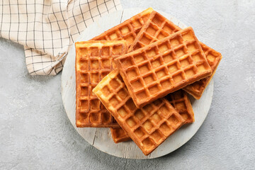 Board with tasty Belgian waffles on light background