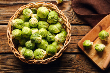 Wicker basket with fresh Brussels cabbage on wooden background