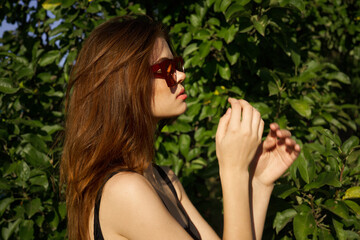 attractive woman posing on the background of green leaves nature