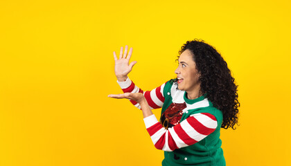 Portrait of Latin mature adult woman holding Christmas gift box on a yellow background in Mexico latin america	
