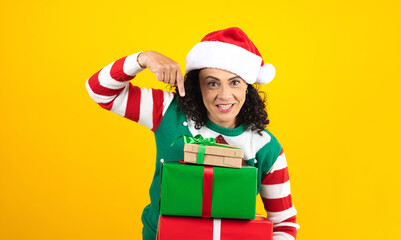 Portrait of Latin senior woman holding Christmas gift box on a yellow background in Mexico latin america	