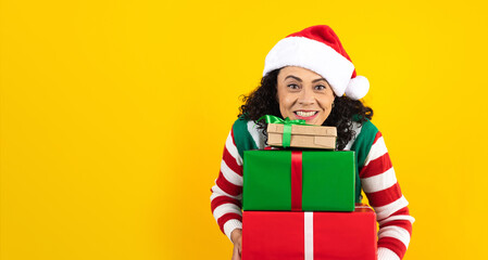 Portrait of Latin senior woman holding Christmas gift box on a yellow background in Mexico latin america	