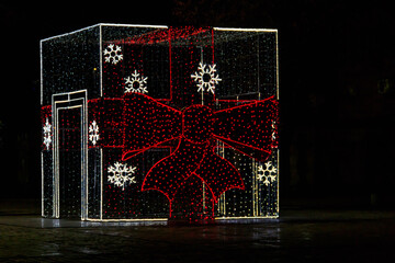 Illuminated Christmas gift box at night. Decoration for Christmas and New Years holidays in a city park