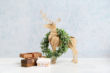 Wooden reindeer, Christmas wreath and gift boxes on color background