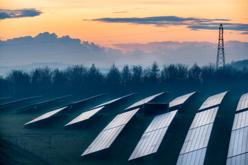 Solar energy park and conventional electricity pylon at sunset,Hampshire,England,UK. - obrazy, fototapety, plakaty
