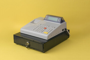 Gray cash register push-button device on a yellow background.