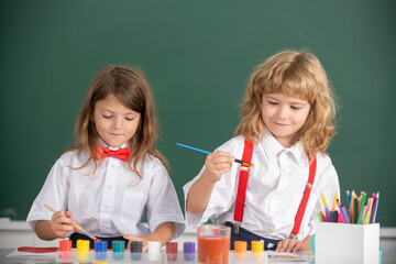 School children drawing a colorful pictures with pencil crayons in classroom. Portrait of cute pupils enjoying art and craft lesson. Kids pupils learning painting.