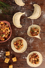 Top view of preparation of empanadas with cheese, egg, onion and cibulet filling. On a rustic wooden table. Vertical image.