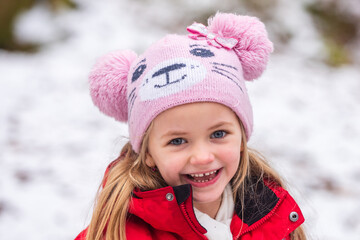 Close up portrait of happy child girl playing on a winter walk in nature. Cute smiling kids face.