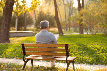 Senior Chinese man reading book in the park