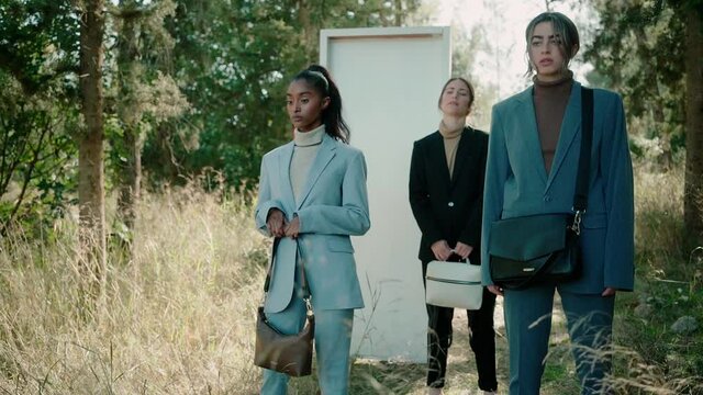 A group of beautiful girls pose for the camera wearing trendy suits and bags