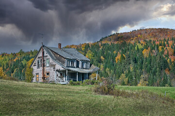 Storm clouds gathering over a dilapidated old home