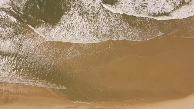 Ocean waves gently crushing into an yellow sand beach, drone moving to the right. 4K, 60 fps