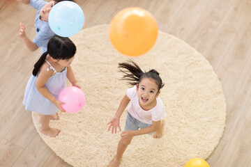 Cute Chinese children playing with balloons in living room