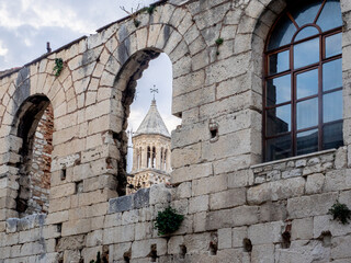 Ancient tower appears through arched stone window in wall surrounding Split, Croatia. 