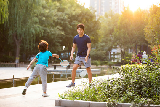 Happy father and son playing badminton in park