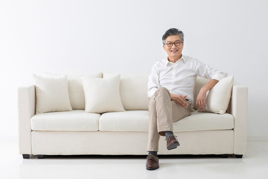 Cheerful senior Chinese man sitting on sofa