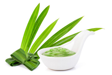 Pandan custard cream in  ceramic spoon and fresh green pandan leaves isolated on white background.