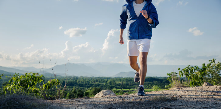 Young man running over rocky trail on the mountain workout outdoors in summer.
