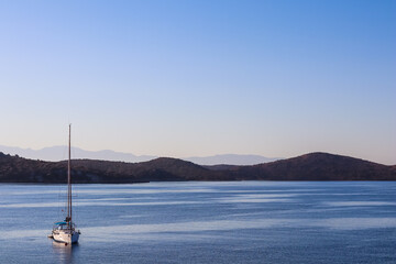 Fototapeta na wymiar Blue sea, a boat and mountains in sunrise. Tranquil seascape and coastal nature concept