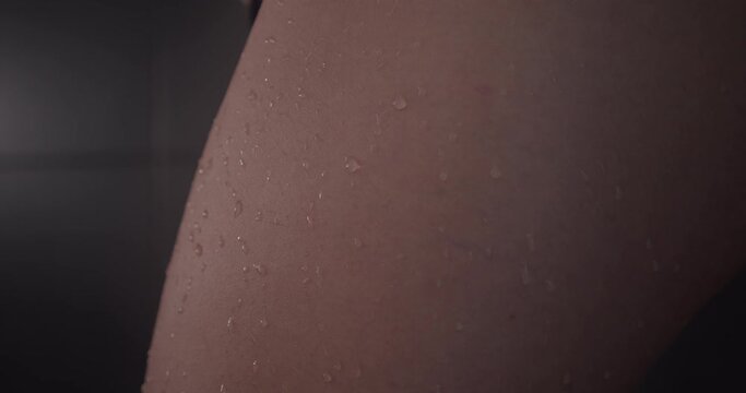 Super close up on water beading on a naked young lady's leg, slow motion.