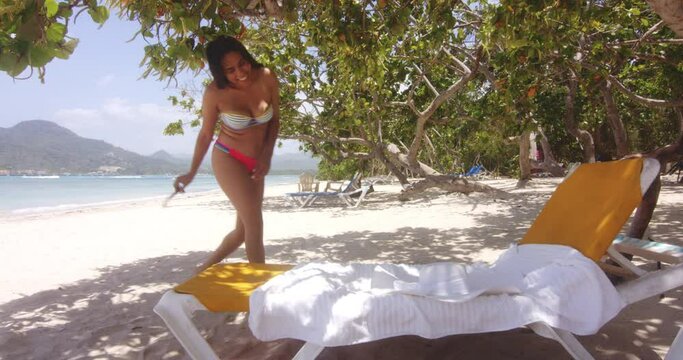 Happy Latino Lady Walks to Sun Lounger to Rest at Playa Teco Maimon Exotic Beach Resort, wide shot