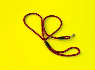 Naklejka premium Heart shaped dog leash placed on a yellow background. Isolated.