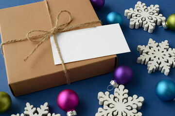 New Year's or Christmas composition. Holiday Gift, white snowflakes, multicolored glass balls for decorating a Christmas tree and a empty festive greeting card with space for your text or logo